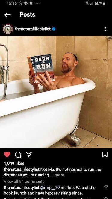 A man in a bath reading a book called 'born to run'