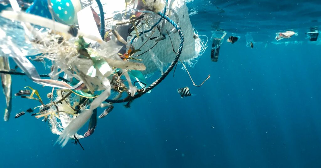 Underwater view showing a collection of plastic debris floating in the ocean, highlighting the issue of marine pollution.