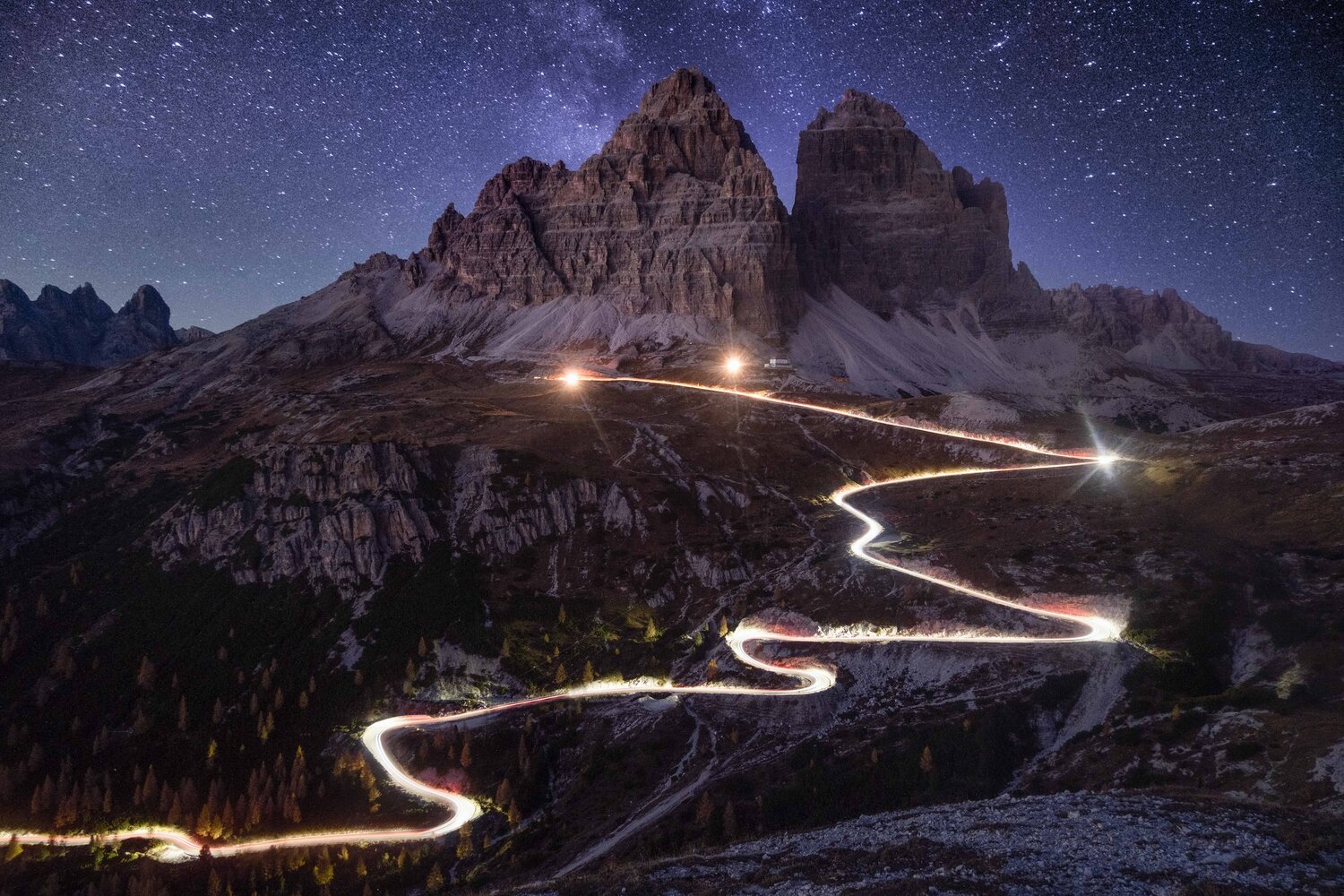 Winding road through the mountains at night under a starry sky