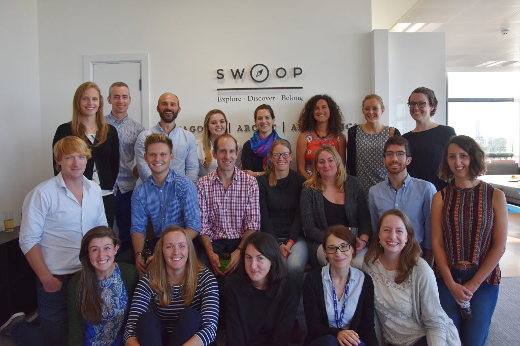 A photo of 20 adults -colleagues- smiling with the company name Swoop behind them.